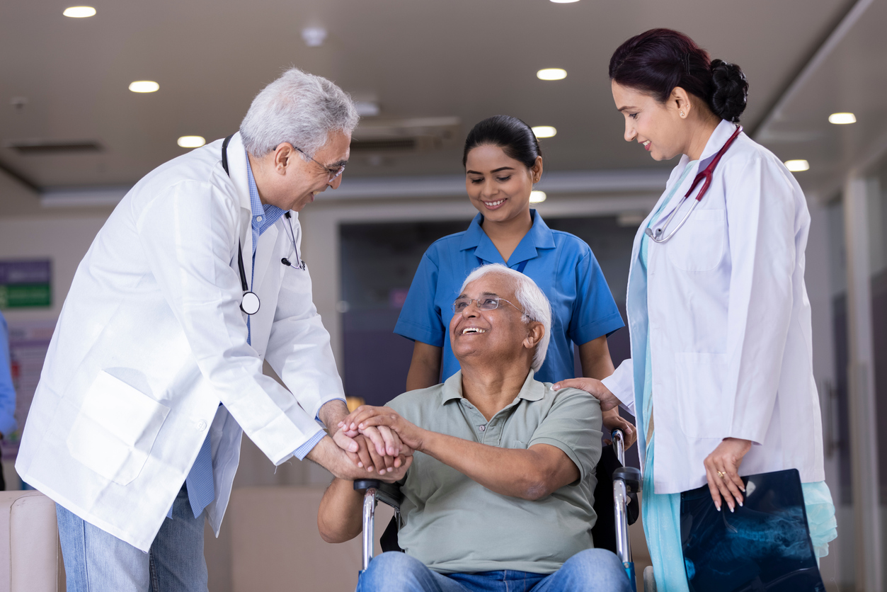 A patient in a wheelchair shakes an orthopedic doctor’s hand as he leaves the practice